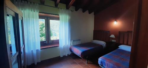 1 dormitorio con 2 camas y ventana en El Serrat Turisme Rural, en Planoles