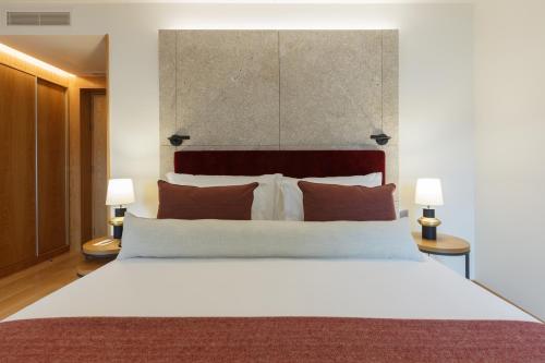 a bedroom with a large white bed with two lamps at NEYA Porto Hotel in Porto