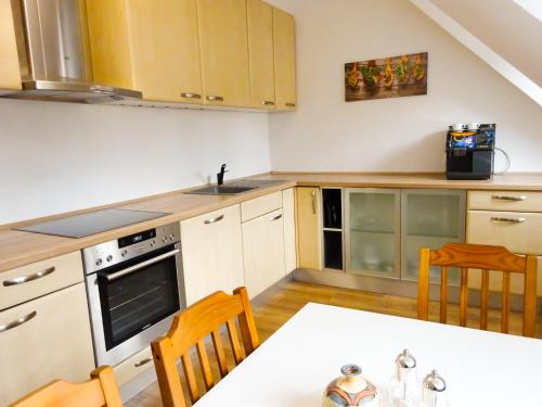 uma cozinha com armários brancos e uma mesa com cadeiras em Krugs Haus Ferienwohnungen Wasserkuppe em Ebersburg