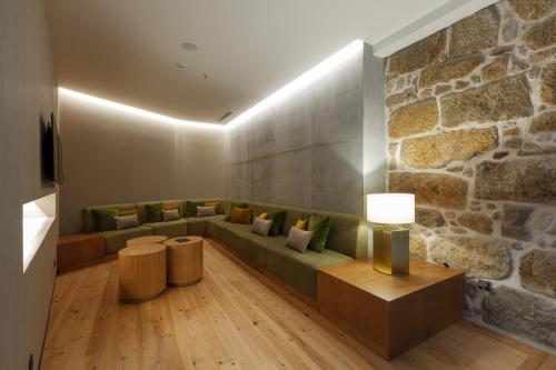 a living room with a couch and a stone wall at NEYA Porto Hotel in Porto
