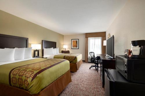 a hotel room with two beds and a desk at Baymont by Wyndham Augusta West in Augusta