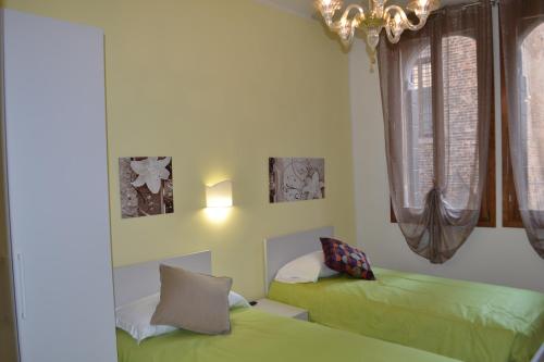 una camera con 2 letti verdi e un lampadario a braccio di Ca' Bacio della Luna a Venezia
