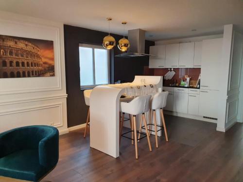 una cocina con armarios blancos y un bar con taburetes en Rome Apartment en Rheineck