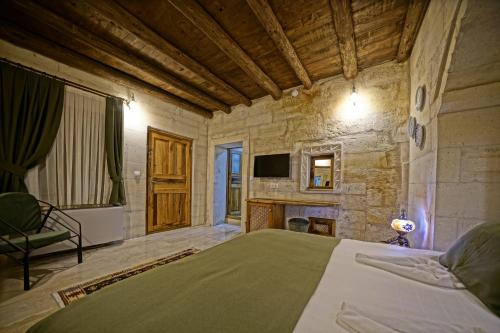 a bedroom with a large bed and a fireplace at Vigneron Cave Hotel in Nevsehir