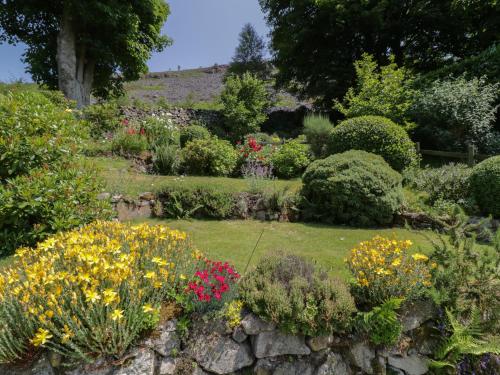 a garden with colorful flowers and a stone wall at Haulfryn in Llangynog