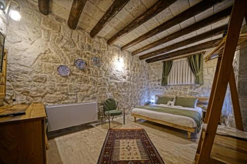 a bedroom with a bed and a stone wall at Vigneron Cave Hotel in Nevsehir