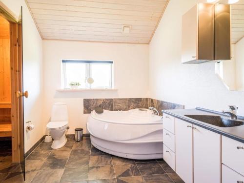 a bathroom with a tub and a toilet and a sink at Holiday home Tarm XLVIII in Tarm