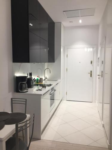 a kitchen with white cabinets and a door and a table at Dune B Apartment in Mielno