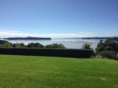 a grassy field with a view of the water at Mangawhai Bay B&B in Omokoroa