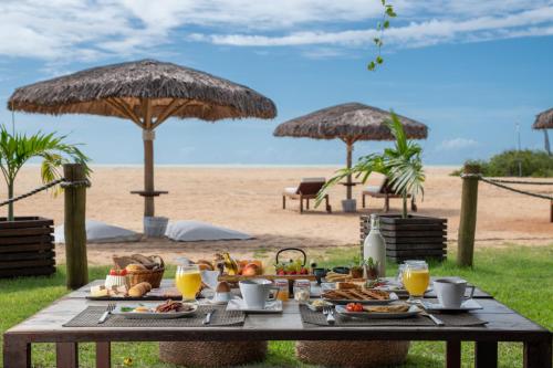 a picnic table with food on the beach with umbrellas at Pousada Mi Secreto in São Miguel do Gostoso
