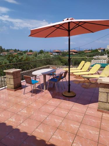 a patio with a table and chairs and an umbrella at Markos apartments 3 in Stoupa