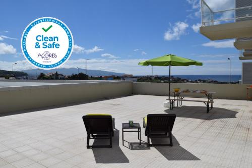 a patio with a table and chairs and an umbrella at Ocean Terrace House in Ribeira Grande