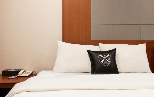 a bed with a black and white pillow and a phone at Incheon Airtel in Incheon