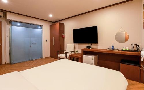 a hotel room with a bed and a desk with a television at Incheon Airtel in Incheon