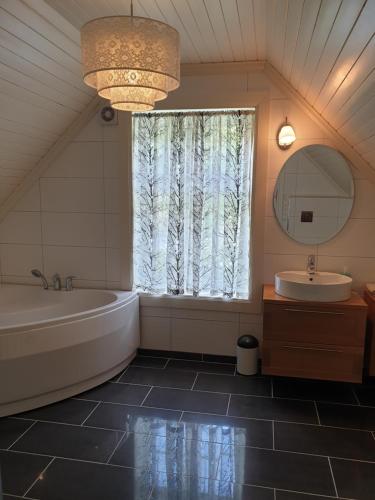 La salle de bains est pourvue d'une baignoire, d'un lavabo et d'une fenêtre. dans l'établissement Irenegarden - Fjord view holiday home, à Lauvstad