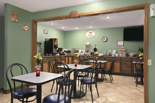 a restaurant with tables and chairs and a kitchen at Super 8 by Wyndham Russellville in Russellville
