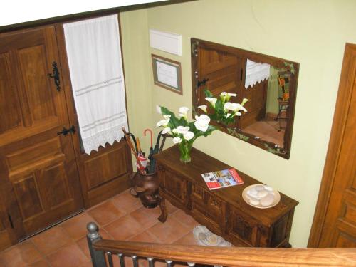 a room with a vase of flowers on a table with a mirror at La Llosa Rodré in Guimarán