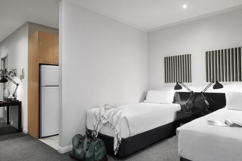 a hotel room with two beds and a refrigerator at Punthill Apartment Hotel - Flinders Lane in Melbourne