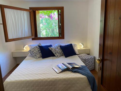 a bedroom with a bed with a book on it at Domus Olivarum - Costa Smeralda 6 guest, 3 room, 2 bathroom, 2 parking Wifi in Abbiadori