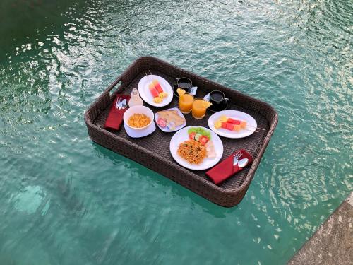 een dienblad met eten op een tafel in het water bij Umagama Ubud Villas in Ubud