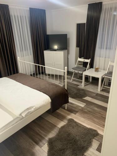 une chambre avec un lit, une télévision et une chaise dans l'établissement Casa De Sub Munte, à Buşteni