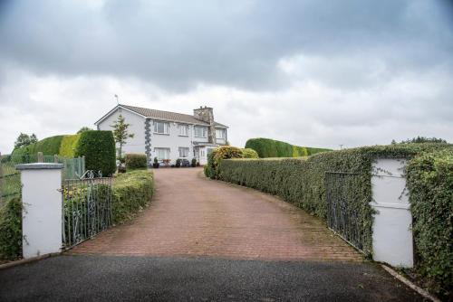 a driveway leading to a white house with a fence at Drom na Gainne B&B in Carrickmore