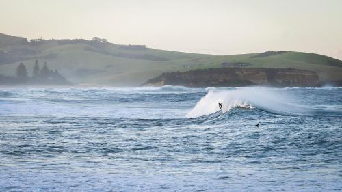 a person riding a wave on a surfboard in the ocean at Werri Beach Holiday Park in Gerringong