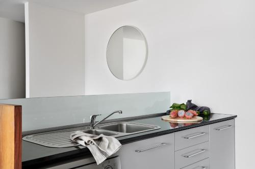 um balcão de cozinha com um lavatório e um espelho em Punthill Apartment Hotel - Little Bourke em Melbourne