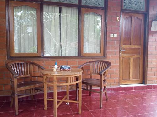 a wooden table and two chairs in front of a brick wall at Madra Homestay in Ubud