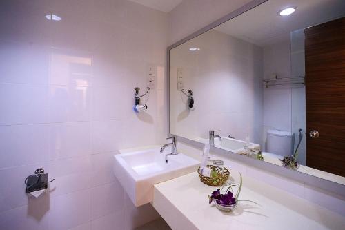 Baño blanco con lavabo y espejo en Bella Vista Express Hotel, en Pantai Cenang