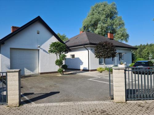a white house with a gate and a driveway at Dom nad jeziorem na Kaszubach in Miszewko