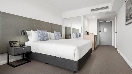 a bedroom with a large white bed and a telephone at Oaks Toowoomba Hotel in Toowoomba