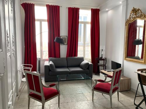モンペリエにあるLa Canourgue, Appart de charme , climatisé,Parking freeのリビングルーム(赤いカーテン、ソファ、椅子付)