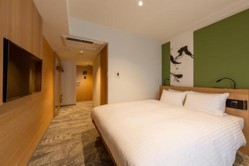a bedroom with a large white bed and a flat screen tv at The OneFive Kyoto Shijo in Kyoto