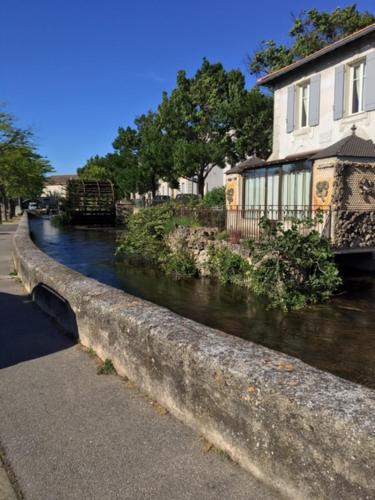 a river next to a building and a house at Maison de charme Isle sur la Sorgue in LʼIsle-sur-la-Sorgue