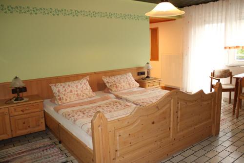 a bedroom with a wooden bed with two pillows at Pension Georgshof in Hilders