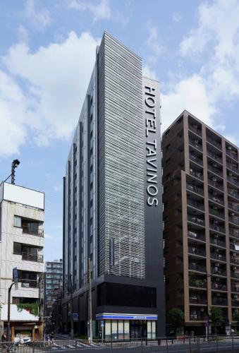 a tall building with a sign on the front of it at HOTEL TAVINOS Asakusa in Tokyo