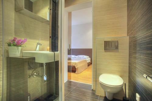 シベニクにあるCasa Marina Apartmentsのバスルーム(洗面台、トイレ付)、ベッド1台が備わります。
