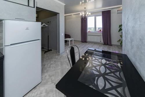 a kitchen with a refrigerator and a table in a room at Квартира- студия "Новая Слободка" in Orenburg