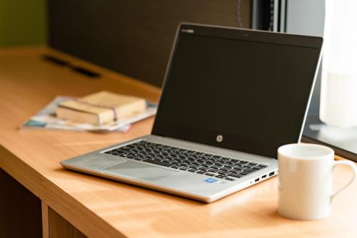 a laptop computer sitting on a desk with a cup of coffee at The OneFive Kyoto Shijo in Kyoto