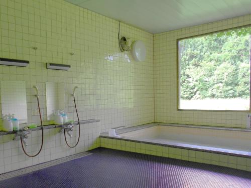 a yellow tiled bathroom with a tub and a window at Hagurosan Sankouin / Vacation STAY 40373 in Tsuruoka