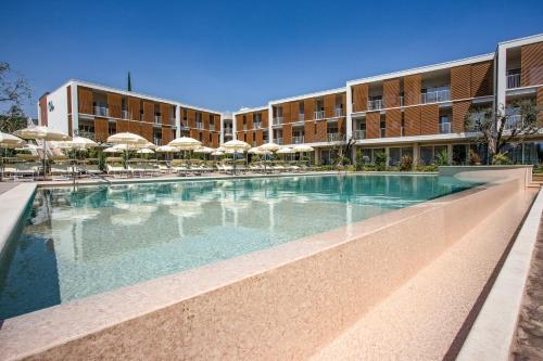 a swimming pool in front of a building with umbrellas at Residenza Olivo in Garda