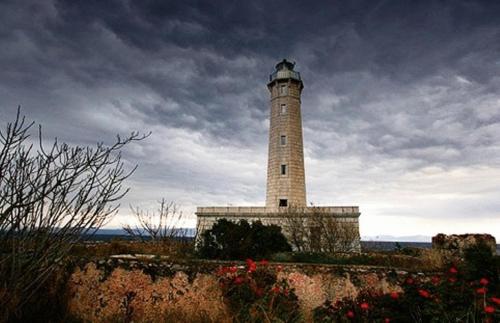 a lighthouse on a hill with a cloudy sky at Aktaion City Hotel in Gythio