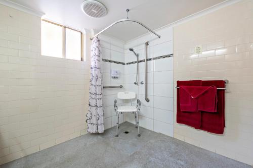 a bathroom with a shower and a red towel at Shearing Shed Motor Inn in Dubbo