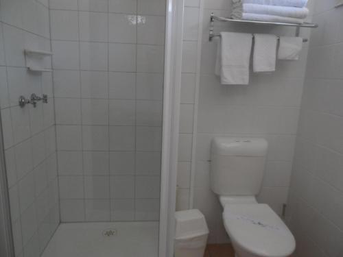 a bathroom with a toilet and a shower with towels at Eastern Sands City Centre in Geelong