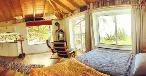 1 Schlafzimmer mit einem Bett, 2 Stühlen und Fenstern in der Unterkunft Quinta dos Artistas in Santa Cruz