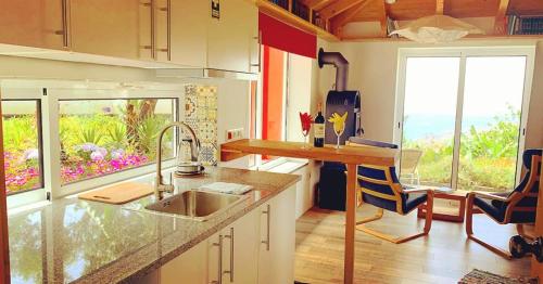 eine Küche mit einem Waschbecken und einer Theke mit einem Fenster in der Unterkunft Quinta dos Artistas in Santa Cruz