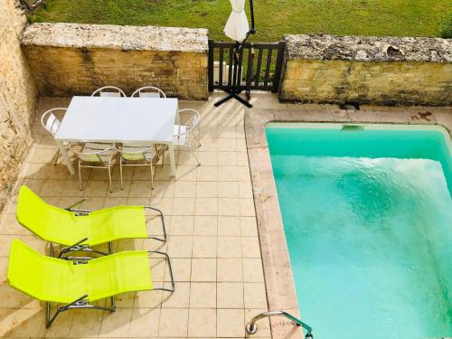 einen Tisch und Stühle neben einem Pool in der Unterkunft Gîte Chez Zoa in Gignac