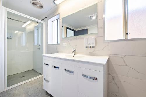 a white bathroom with a sink and a shower at Comfort Inn Shearing Shed in Dubbo