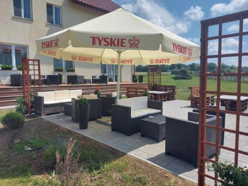 a patio with tables and chairs and an umbrella at Przystanek Czapla in Czaplinek